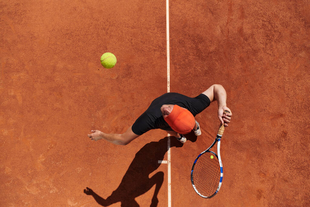 Profesyonel bir tenisçinin üst görüntüsü, tenis topunu hassas ve güçlü bir şekilde sahada servis eder..  - Fotoğraf, Görsel