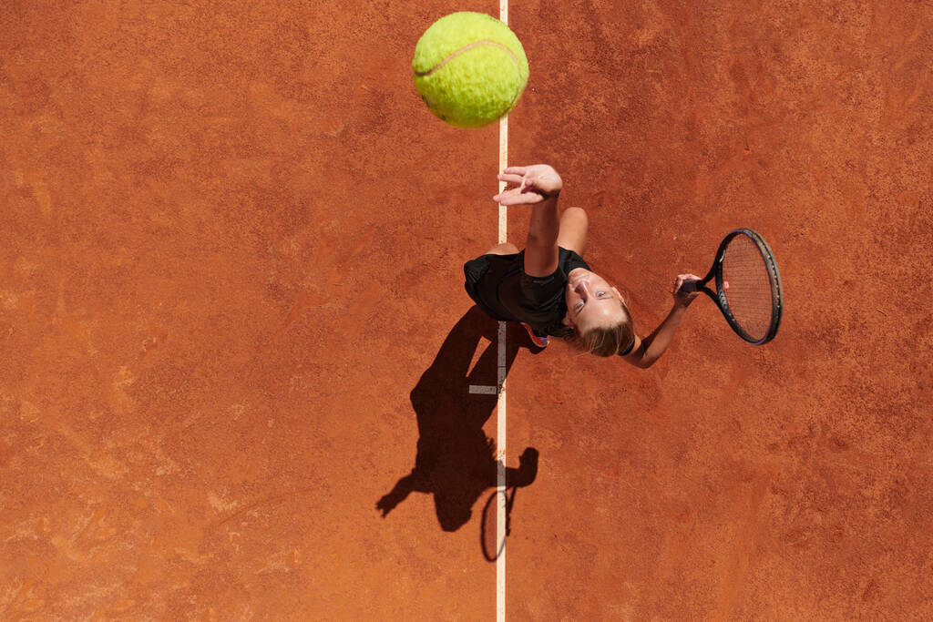 Vista dall'alto di una tennista professionista serve la palla da tennis sul campo con precisione e potenza.  - Foto, immagini