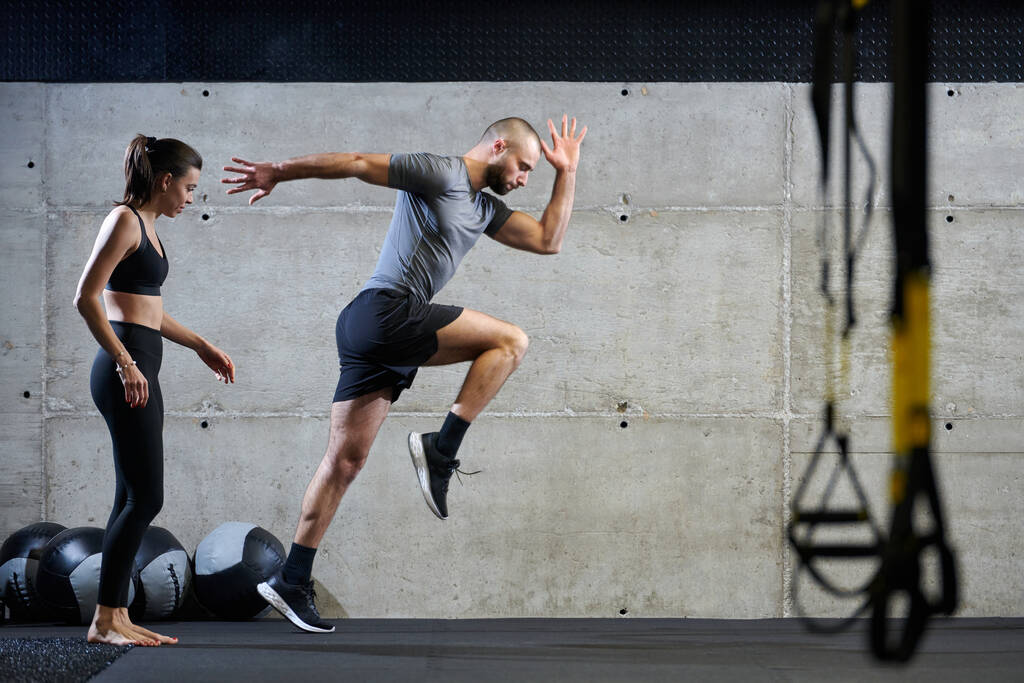 Una pareja en forma en un gimnasio moderno, realizando ejercicios de carrera y mostrando su destreza atlética con un comienzo dinámico - Foto, imagen