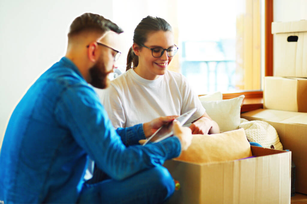 Cute couple unpacking cardboard boxes in their new home. - Photo, Image