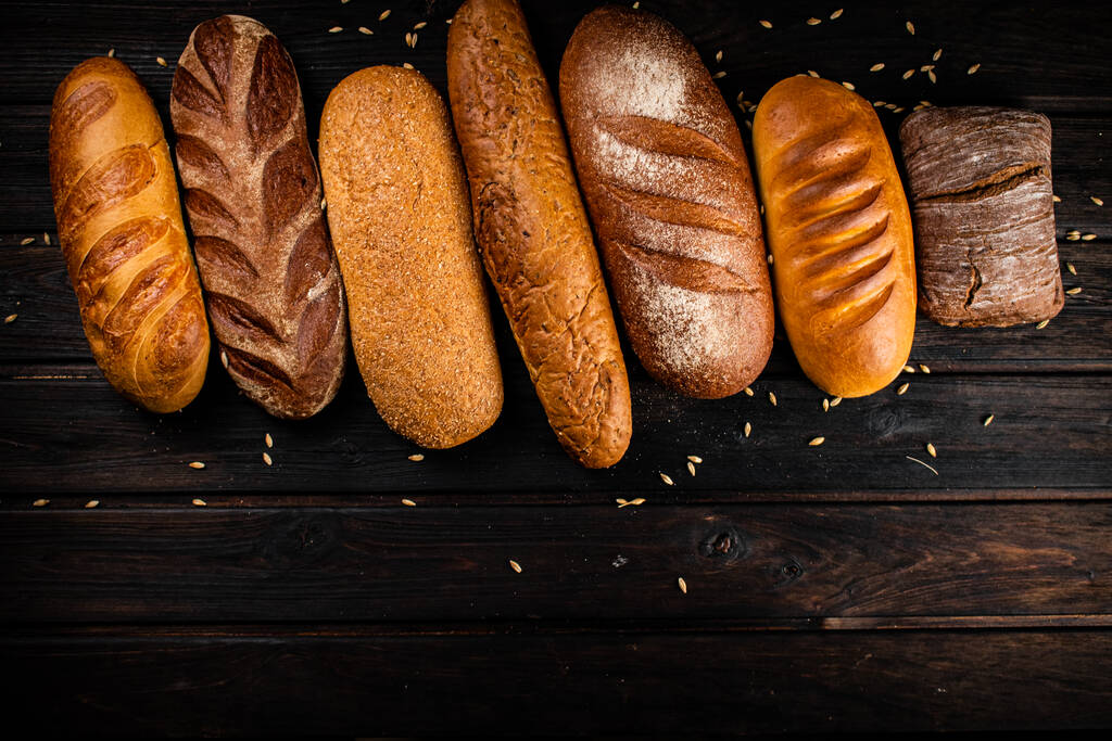 Verschiedene Arten von frischem knusprigem Brot. Auf einem hölzernen Hintergrund. Hochwertiges Foto - Foto, Bild