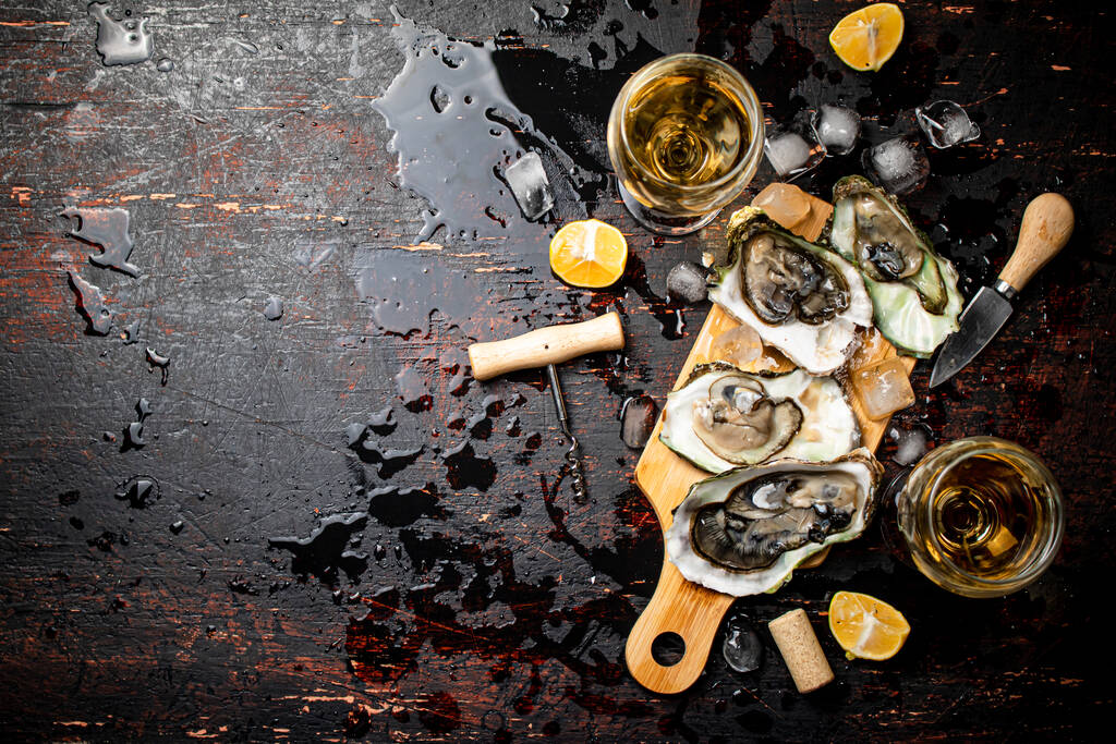 Oysters on a wooden cutting board. On a rustic dark damp background. High quality photo - Foto, Bild