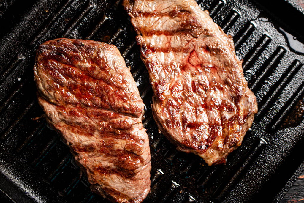 Steak grillé aromatique dans une poêle. Sur un fond sombre. Photo de haute qualité - Photo, image