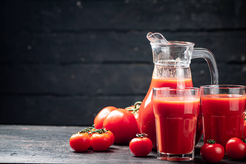 テーブルの上に熟したトマトからジュース。黒い木の背景に。高品質の写真 - 写真・画像