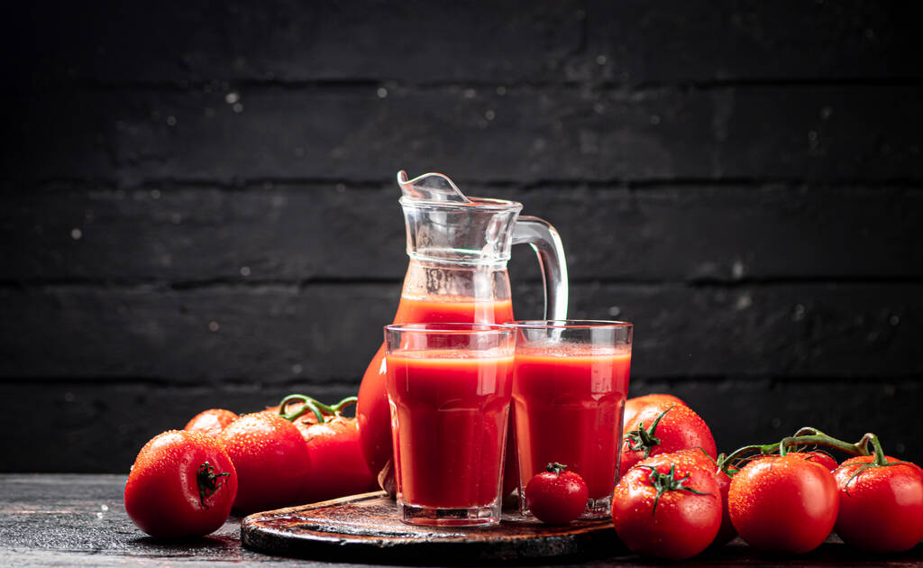 Juice from ripe tomatoes on the table. On a black wooden background. High quality photo - Photo, Image
