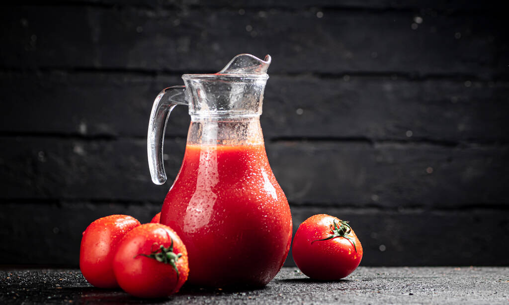 Fresh tomato juice in a jug. On a wooden background. High quality photo - Фото, изображение