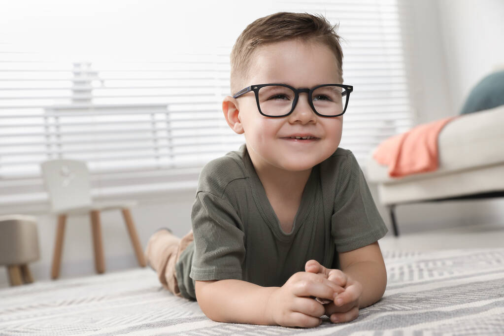 Słodki chłopczyk w okularach na podłodze w domu. Miejsce na tekst - Zdjęcie, obraz