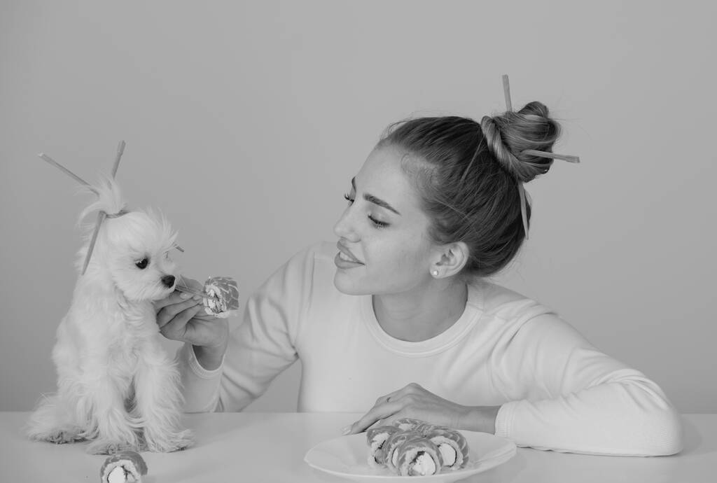 Belleza mujer sexy con perro comiendo sushi. Rollos de sushi. Chica modelo de moda comiendo Sushi con palillos. Maquillaje perfecto y corte de pelo bob con palillos, comida japonesa - Foto, imagen