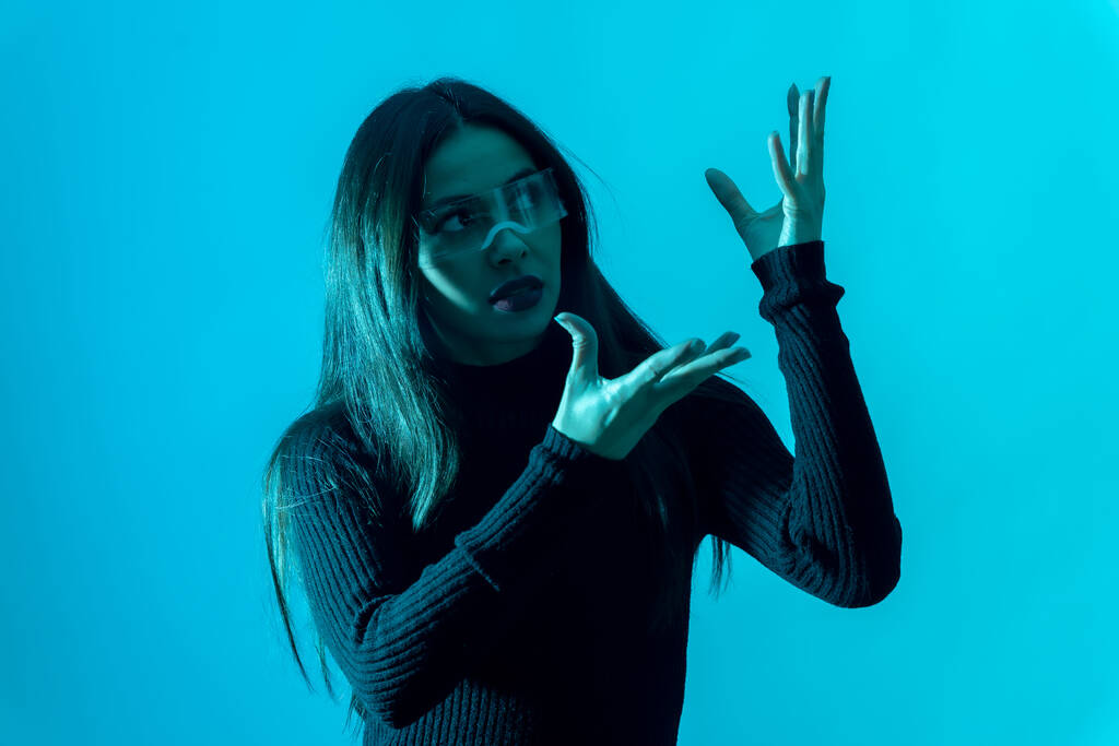 Technologie concept. Portret van vrouw in futuristische bril met led-licht op een blauwe achtergrond - Foto, afbeelding