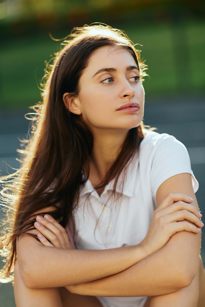 portrait of young woman with brunette long hair and natural makeup posing with crossed arms in white polo shirt and looking away, blurred background, Miami, Florida, iconic city,  - Photo, Image