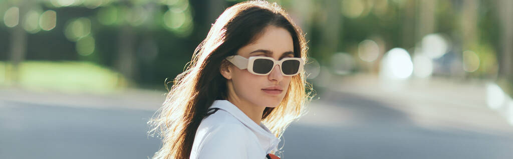 Porträt einer stilvollen jungen Frau mit brünetten langen Haaren im weißen Poloshirt und Sonnenbrille mit verschwommenem Hintergrund, Miami, ikonische Stadt, Florida, sonniger Tag, Banner - Foto, Bild