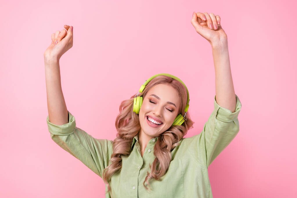 Foto de alegre adorable dama usar camisa verde ojos cerrados disfrutando de auriculares aislados de color rosa de fondo. - Foto, imagen