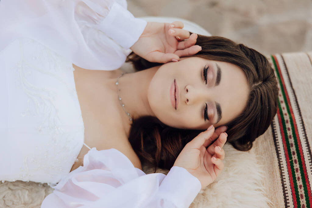 A woman in a white airy dress lies on the floor with her eyes closed. The concept of loneliness and balance. Close-up portrait. - Photo, Image