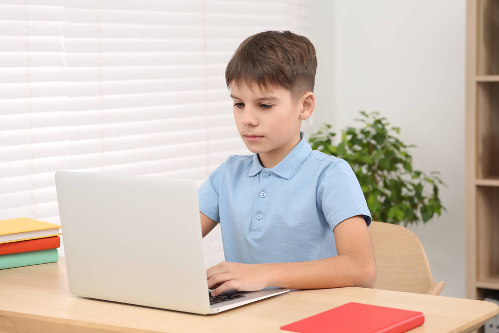 Chłopak korzystający z laptopa w pokoju. Miejsce pracy w domu - Zdjęcie, obraz