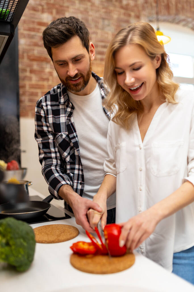 Glückliches Paar kocht gemeinsames Abendessen in der Küche zu Hause und bereitet Gemüsesalat zum Frühstück zu. - Foto, Bild
