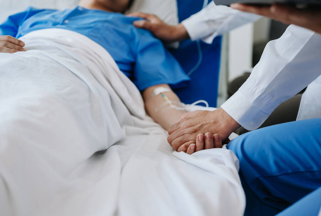 Γυναίκα γιατρός κρατώντας το χέρι του άνδρα ασθενή στο κρεβάτι στο νοσοκομείο  - Φωτογραφία, εικόνα