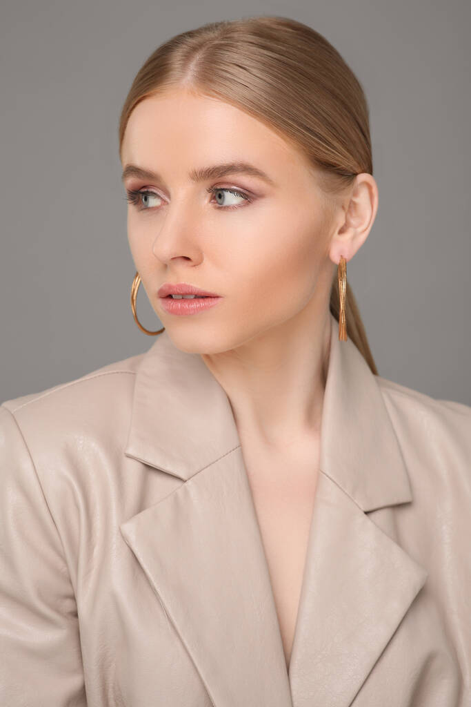 Mooie jonge vrouw met elegante oorbellen op grijze achtergrond - Foto, afbeelding