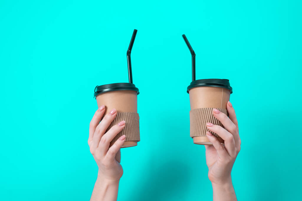 A woman holds two cardboard cups with coffee on a blue background - Photo, Image