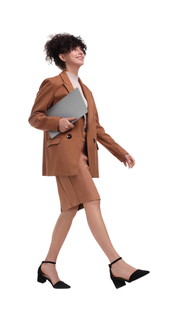 Belle femme d'affaires heureuse avec ordinateur portable marchant sur fond blanc - Photo, image