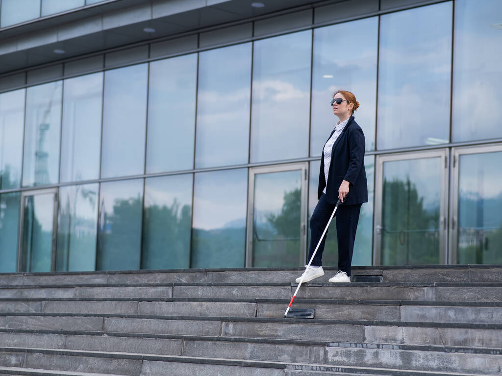 Mulher de negócios cega descendo escadas com uma bengala tátil de um centro de negócios - Foto, Imagem