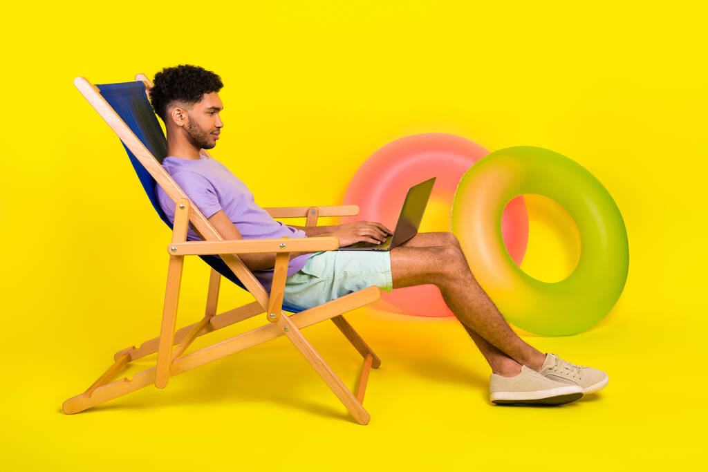 若い男うそsunbed休暇日光浴近くビーチとともにnetbook書き込み彼のsmm blog孤立した上に黄色の色の背景. - 写真・画像