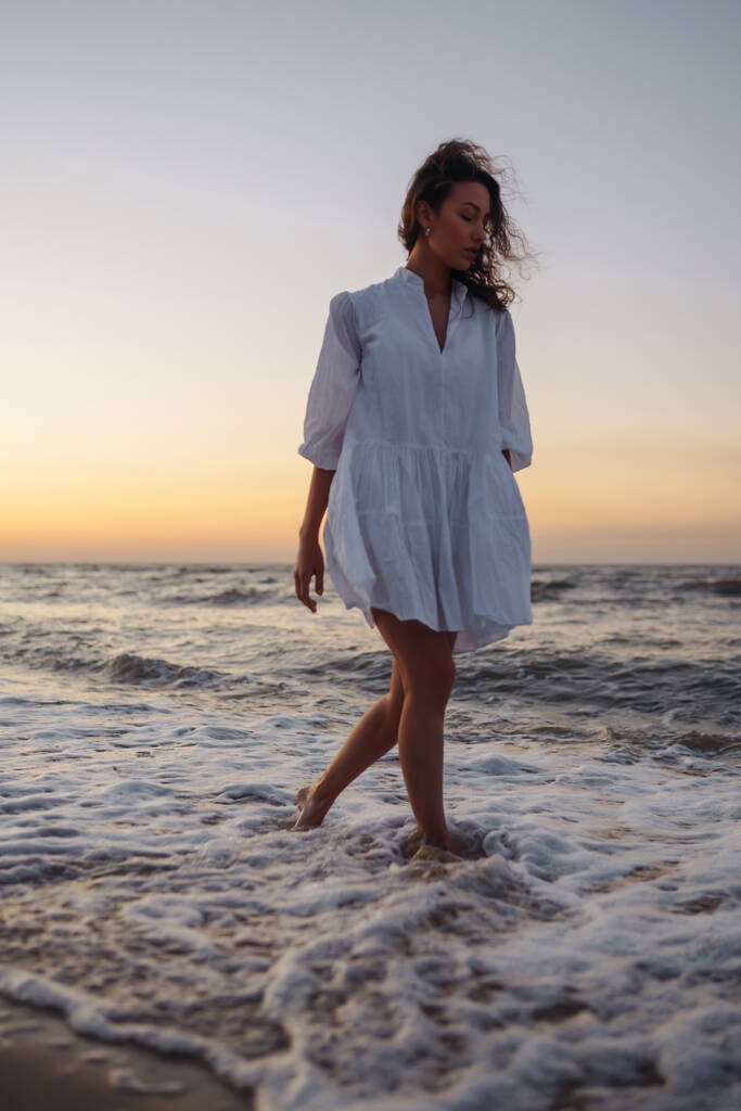 Krásná žena kráčí na pláži při západu slunce. Léto. Cestování, víkend, relaxace a životní styl koncept. - Fotografie, Obrázek