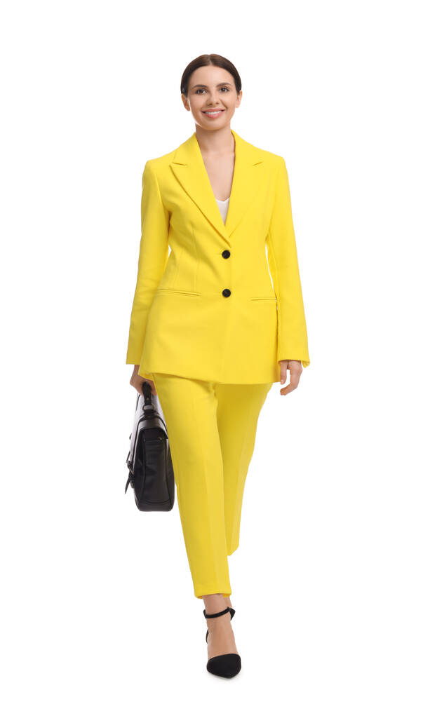 Όμορφη επιχειρηματίας σε κίτρινο κοστούμι με χαρτοφύλακα περπάτημα σε λευκό φόντο - Φωτογραφία, εικόνα