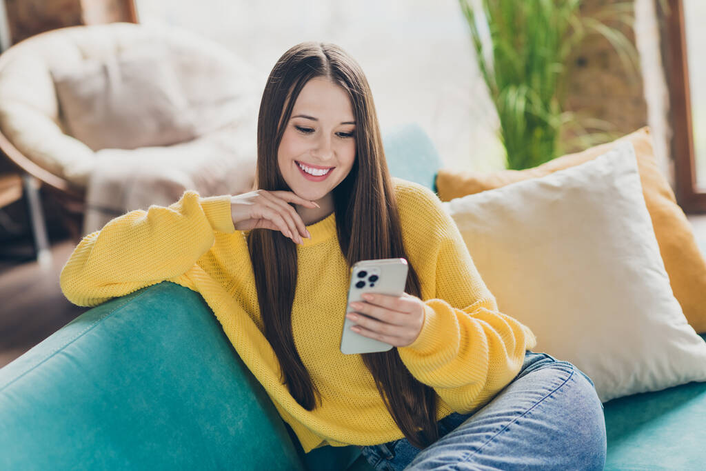 Foto de menina bonita alegre sentar sofá confortável sorriso usar telefone inteligente conversando tempo livre apartamento moderno dentro. - Foto, Imagem