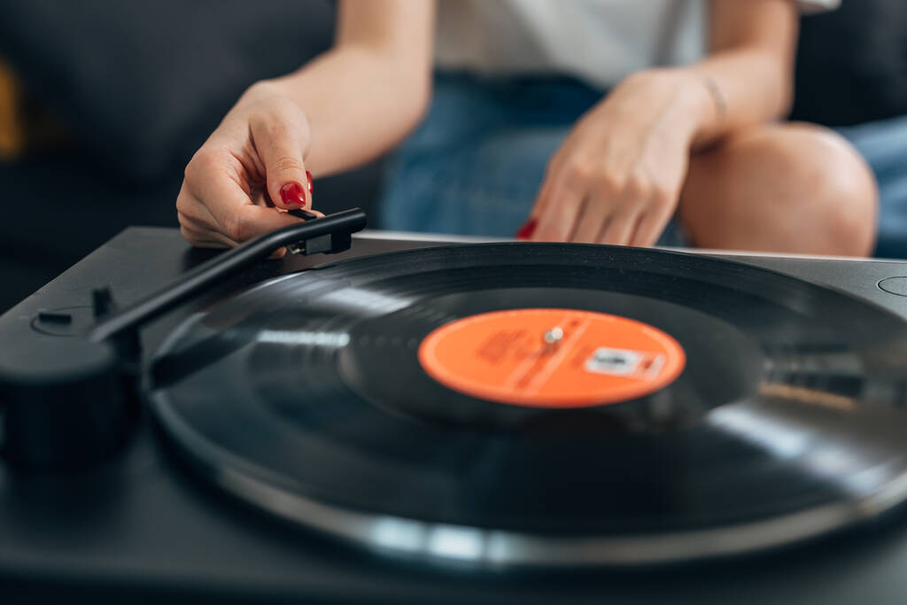Primo piano di una donna mano mettendo uno spillo su un disco in vinile per riprodurre una canzone. - Foto, immagini