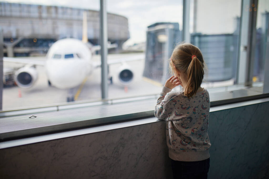 Το κορίτσι του νηπιαγωγείου στο διεθνές αεροδρόμιο, κοιτάζει από το παράθυρο τα αεροπλάνα. Ταξίδι με τα παιδιά έννοια - Φωτογραφία, εικόνα