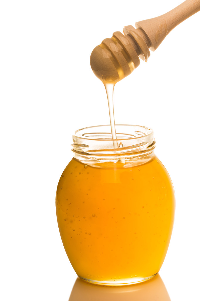Frasco de mel com drizzler de madeira isolado sobre fundo branco
 - Foto, Imagem