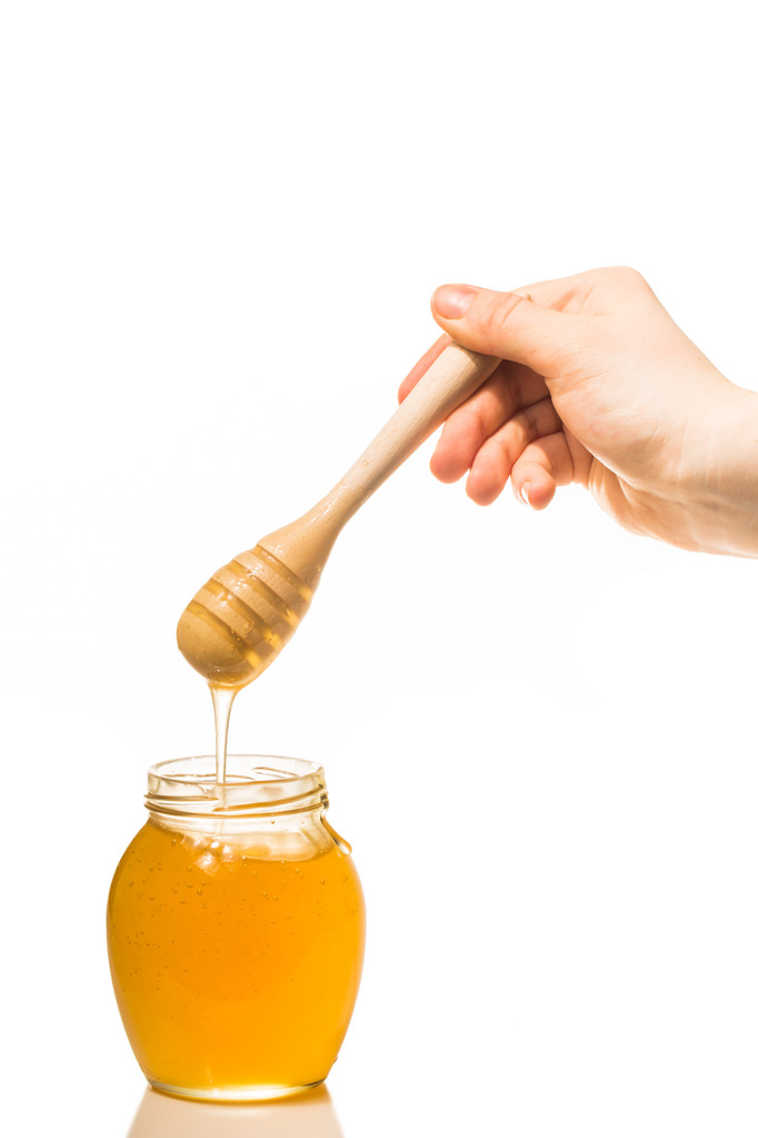 Jar of honey with wooden drizzler isolated on white background - Photo, Image