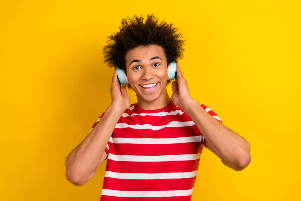 Фото фанк крутого чоловіка в смугастій футболці, насолоджуючись музичними навушниками ізольований жовтий кольоровий фон
. - Фото, зображення
