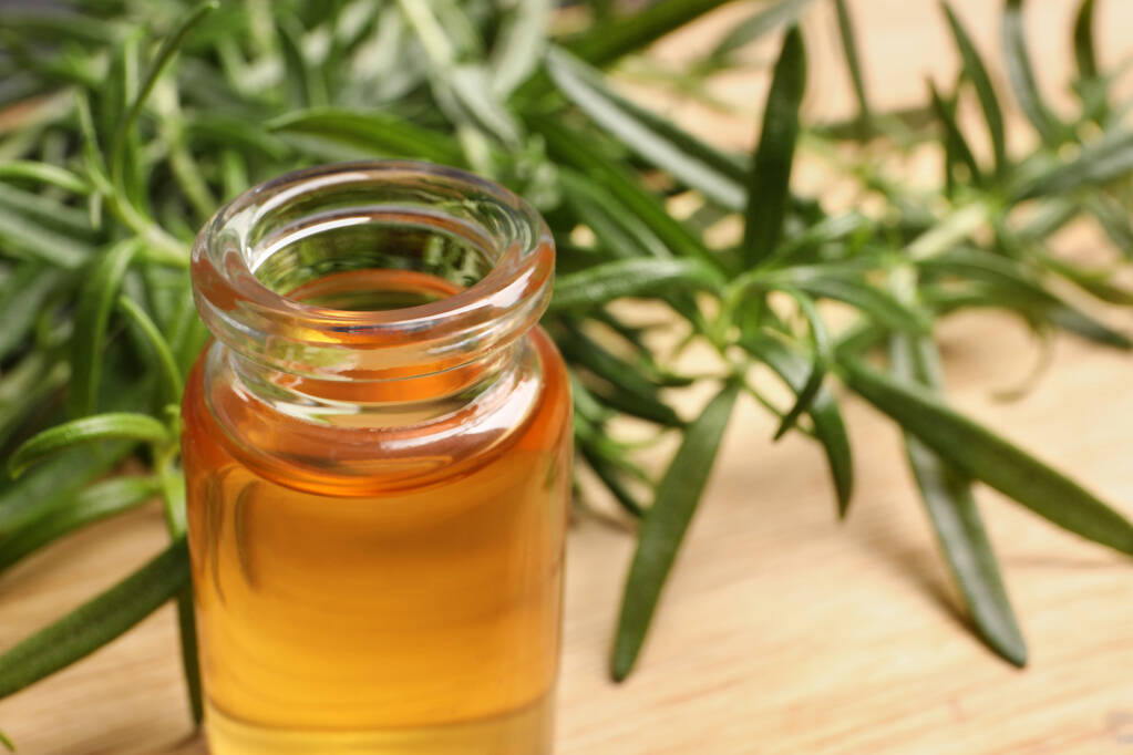 Botella de aceite esencial y ramitas de romero fresco en la mesa, primer plano - Foto, Imagen