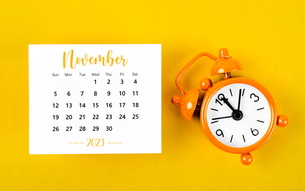 Noviembre 2023 Calendario mensual para 2023 año con despertador de color negro sobre fondo amarillo. - Foto, imagen