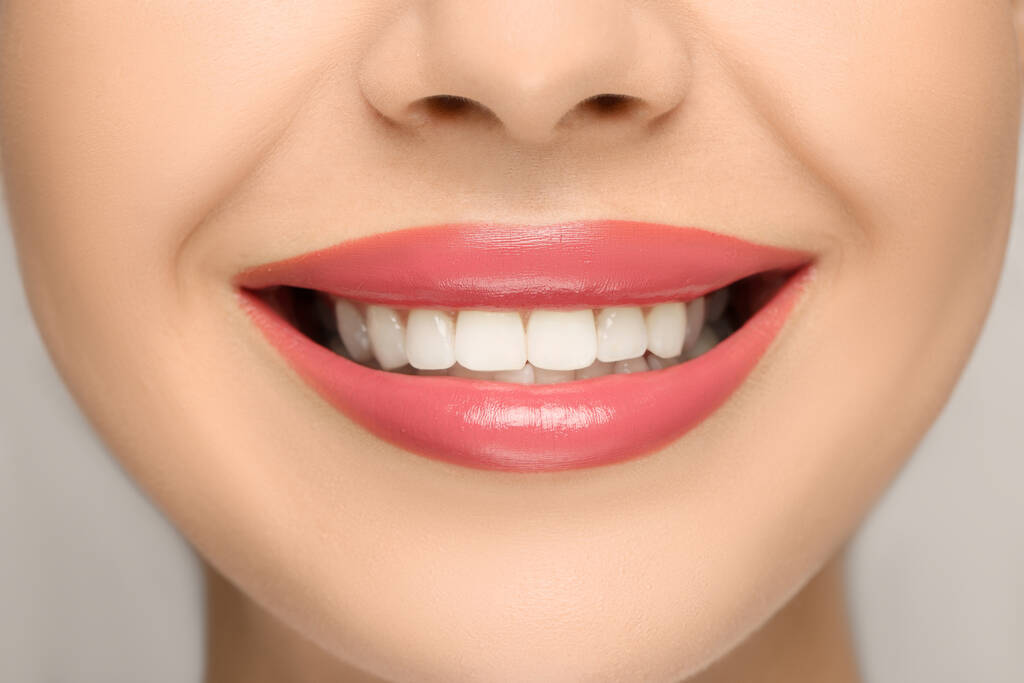 Uśmiechnięta kobieta ze zdrowymi zębami na jasnym tle, zbliżenie - Zdjęcie, obraz