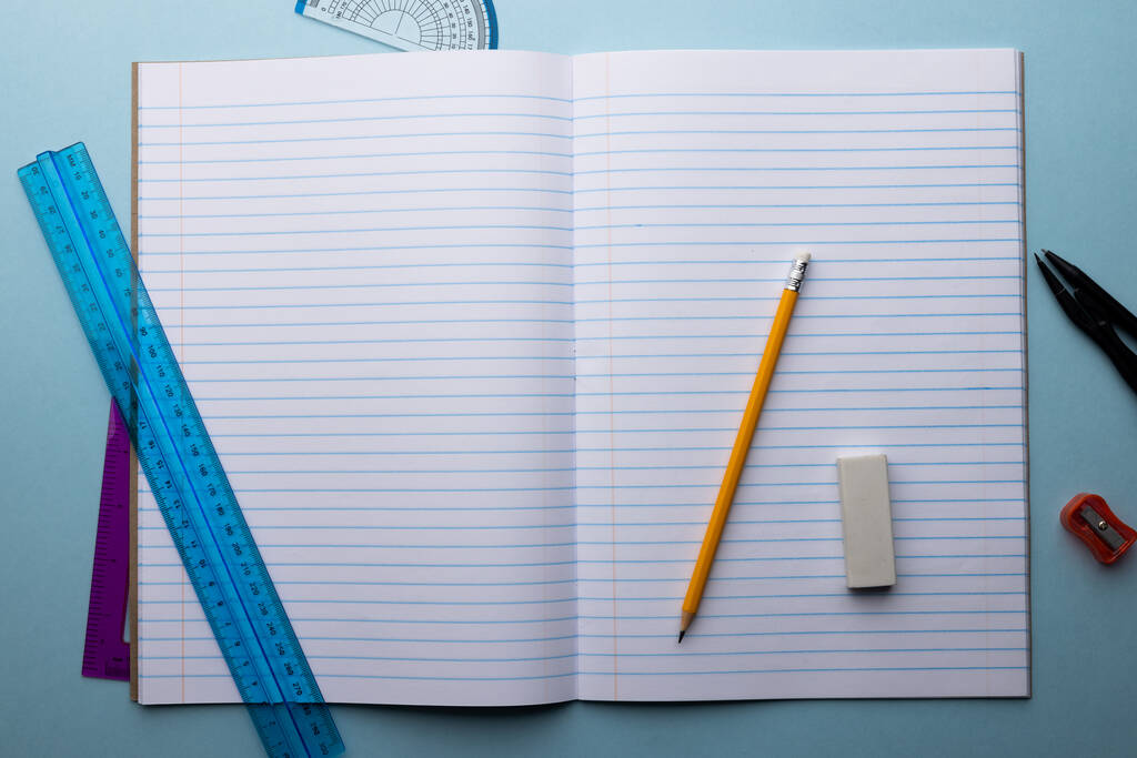 Közelkép a notebook vonalzók és írás anyag kék háttérrel. Iskolai anyagok, matematika, írás, rajz, tanulás, iskolai és oktatási koncepció. - Fotó, kép