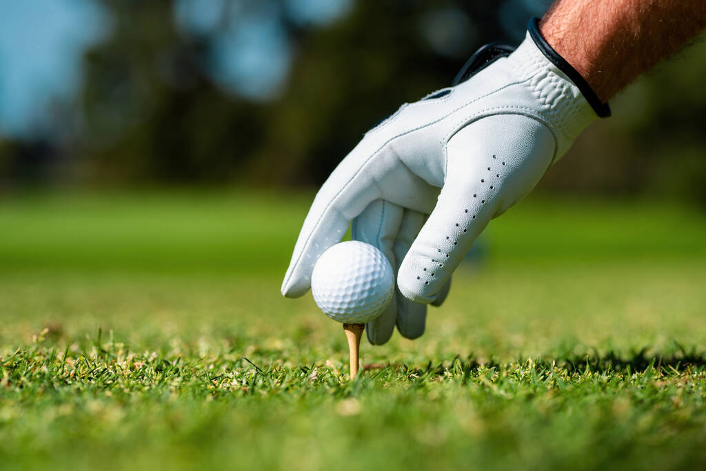 Голфер збиває м'яч по гольфу з ключем. Рука з рукавичкою для гольфу. - Фото, зображення