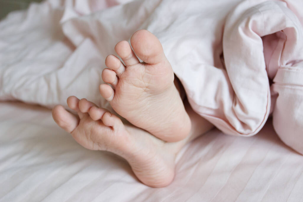 Ayaklarını yatağın üzerinde hafif bir battaniyenin altına koy. Uyumak mı yoksa sabah uyanmak mı? - Fotoğraf, Görsel