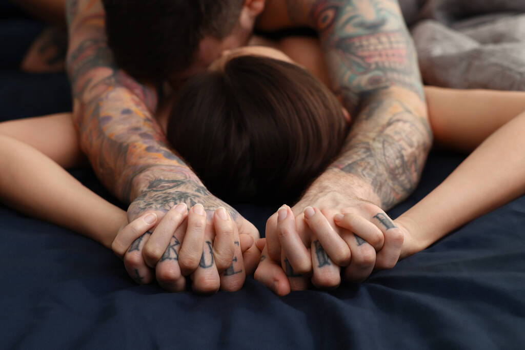 Страстная пара занимающаяся сексом в постели, сосредоточенная на руках - Фото, изображение