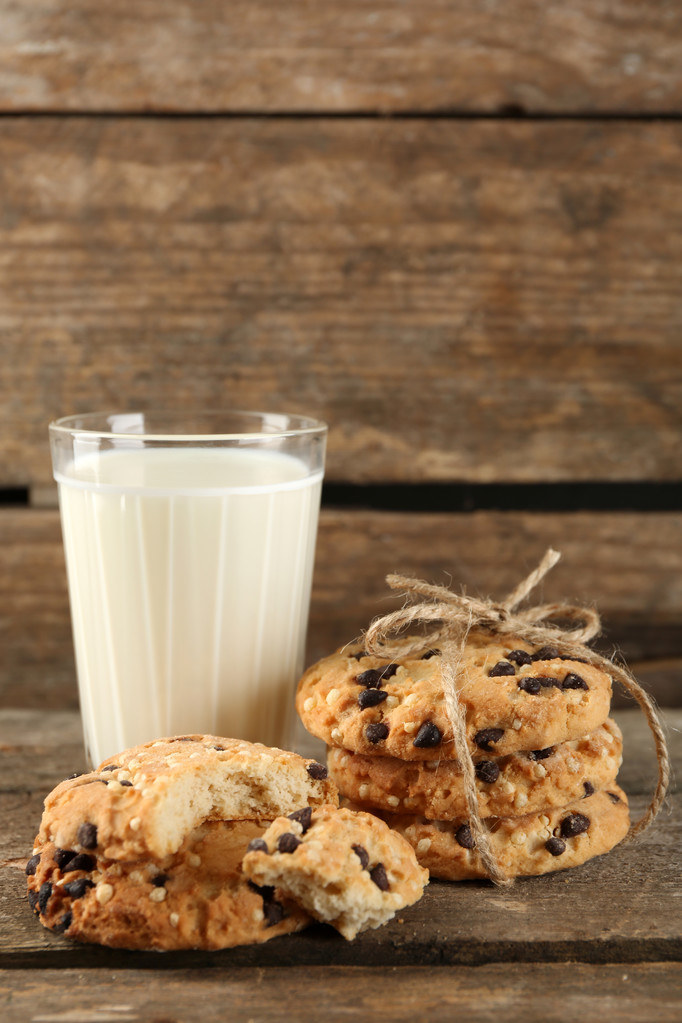 Smakelijke cookies en glas melk op rustieke houten achtergrond - Foto, afbeelding