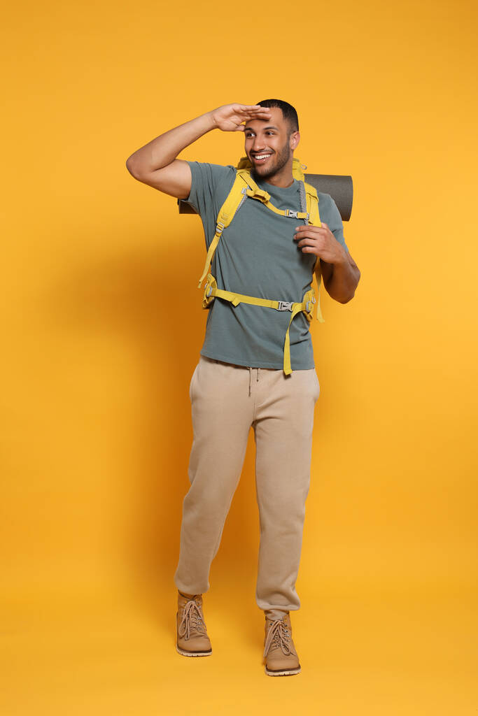 Szczęśliwy turysta z plecakiem na żółtym tle - Zdjęcie, obraz
