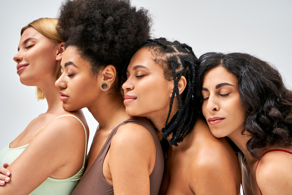 Többnemzetiségű, színes melltartóban álló nők egymás mellett és csukott szemmel, miközben szürke, különböző testtípusokon és önelfogadó koncepción, multikulturális modelleken pózolnak. - Fotó, kép