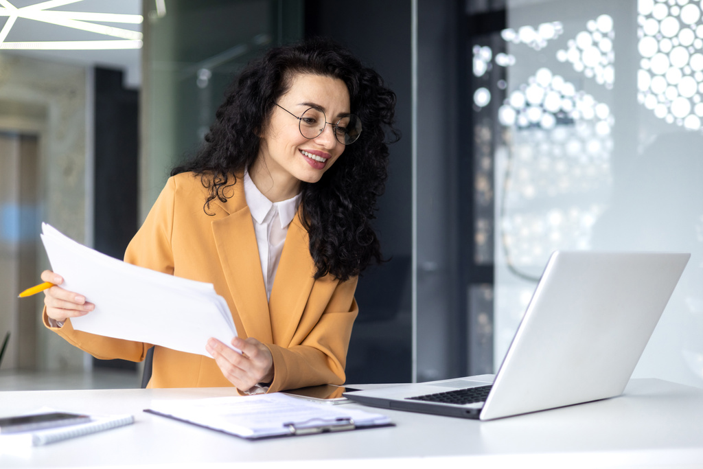 latin american businesswoman working inside office with documents and laptop, worker paperwork calculates financial indicators smiling and happy with success and results of achievement and work. - Photo, Image