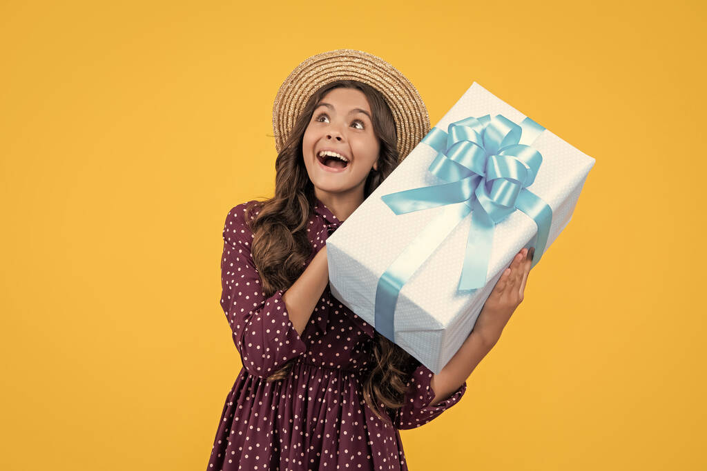 сміється дівчина-підліток з подарунковою коробкою на жовтому фоні
. - Фото, зображення