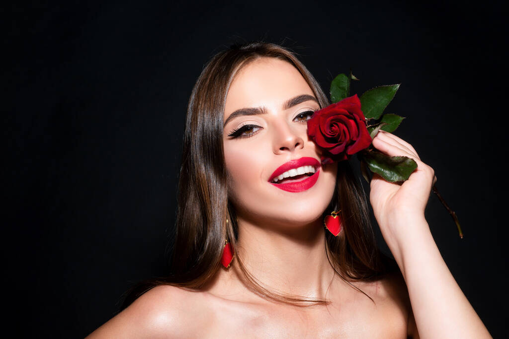 Retrato de cerca de una joven hermosa mujer sexy con rosa roja sobre un fondo negro. Primer plano fresco cara chica - Foto, imagen