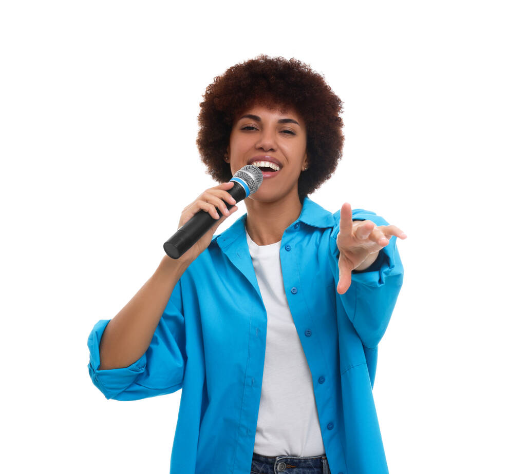 krullend jong vrouw met microfoon zingen op witte achtergrond - Foto, afbeelding