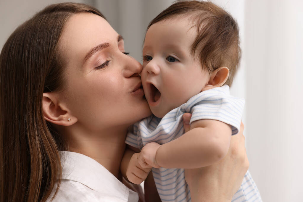 Mutlu anne küçük bebeğini evde öpüyor, yakın plan. - Fotoğraf, Görsel