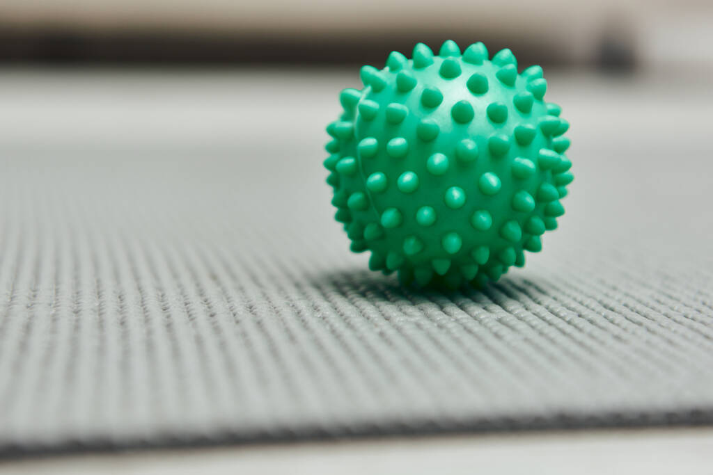 Close up view of handle massage ball on fitness mat on floor at home, natural health practices and home-based massage concept, health and relaxation, beauty and wellness routine  - Photo, Image
