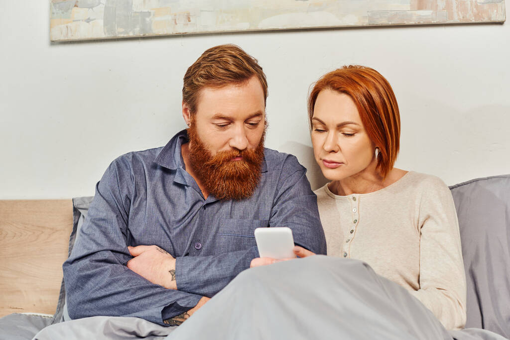 digital couple, screen time, networking, relaxing on weekends without kids, husband and wife, bearded man and redhead woman using smartphone, cozy bedroom, day off, tattooed  - Photo, Image